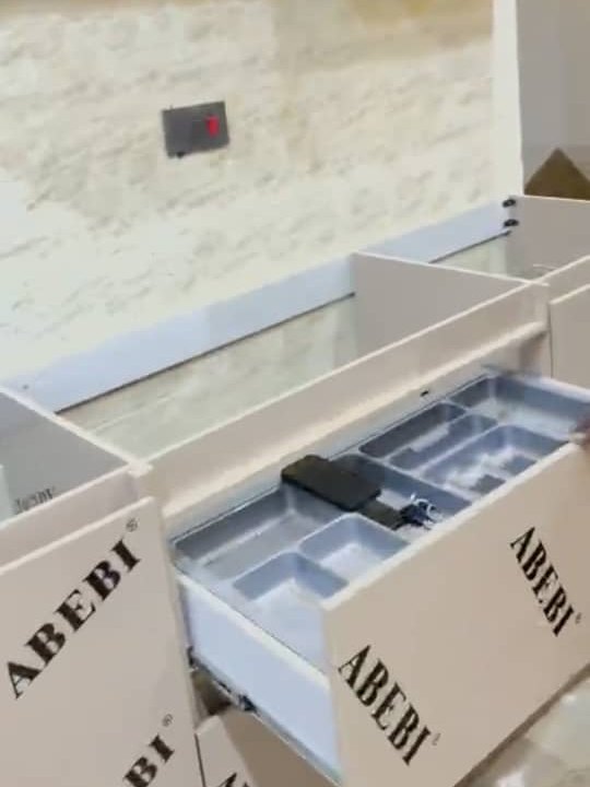 An open drawer with a compartmented cutlery insert, against a marble effect splashback