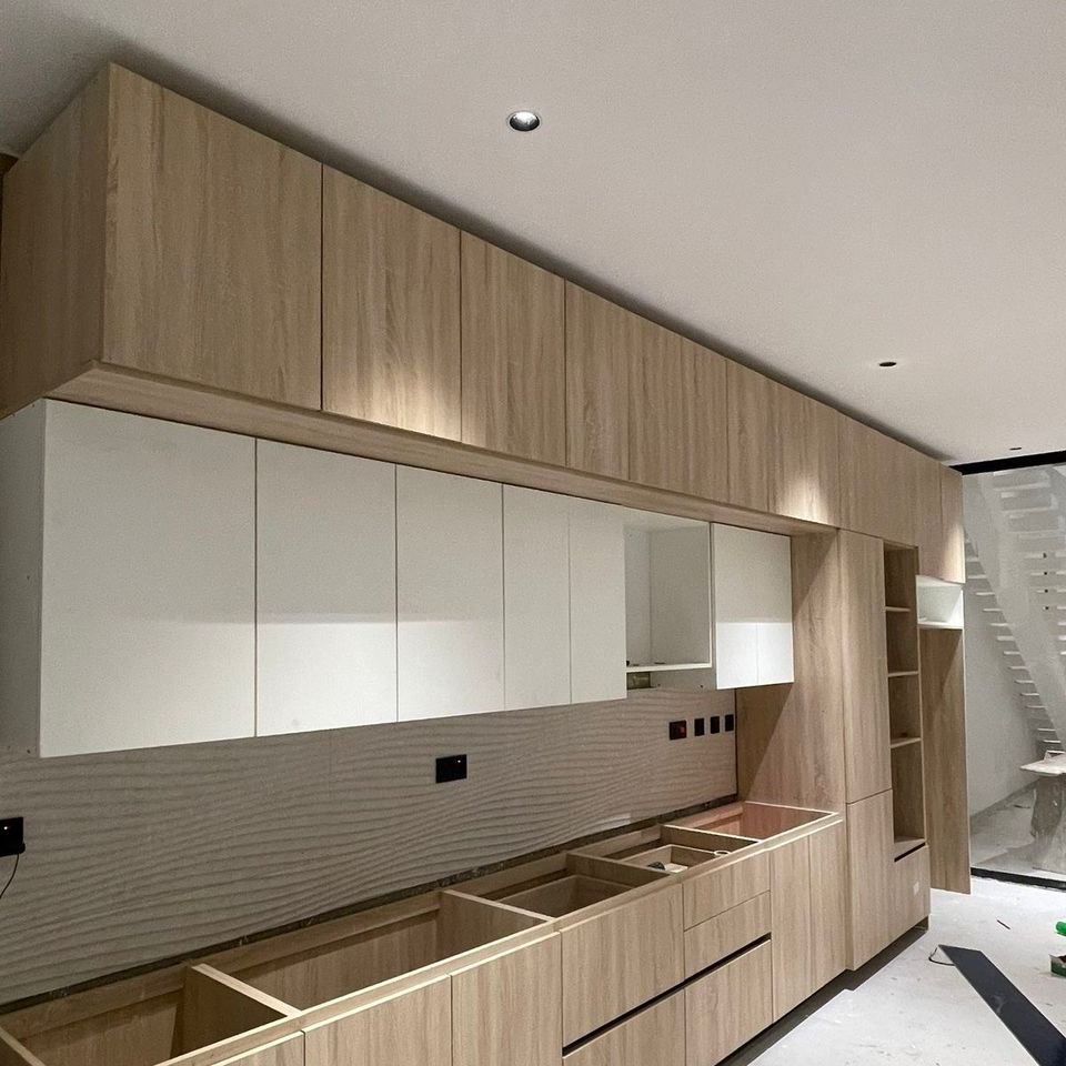 White gloss upper units above light oak base units in a fitted kitchen