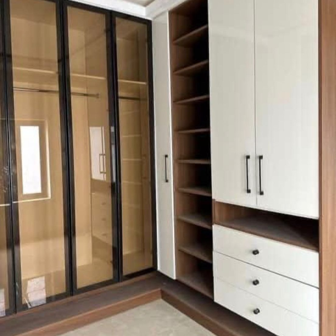 Bronze glass wardrobe doors beside an open walnut shoe tower